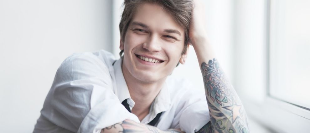 Rapaz tatuado sorrindo.