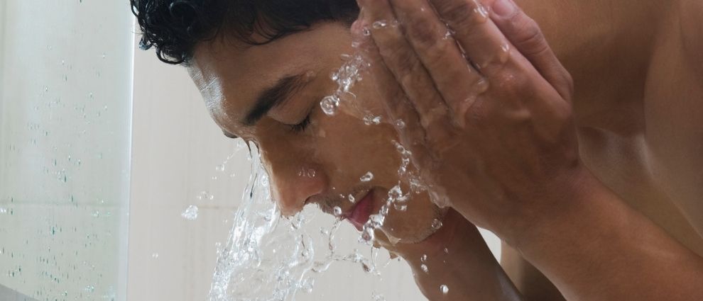Homem lavando o rosto com água.