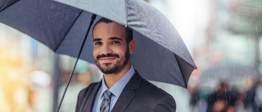 Homem barbudo segurando um guarda-chuva.